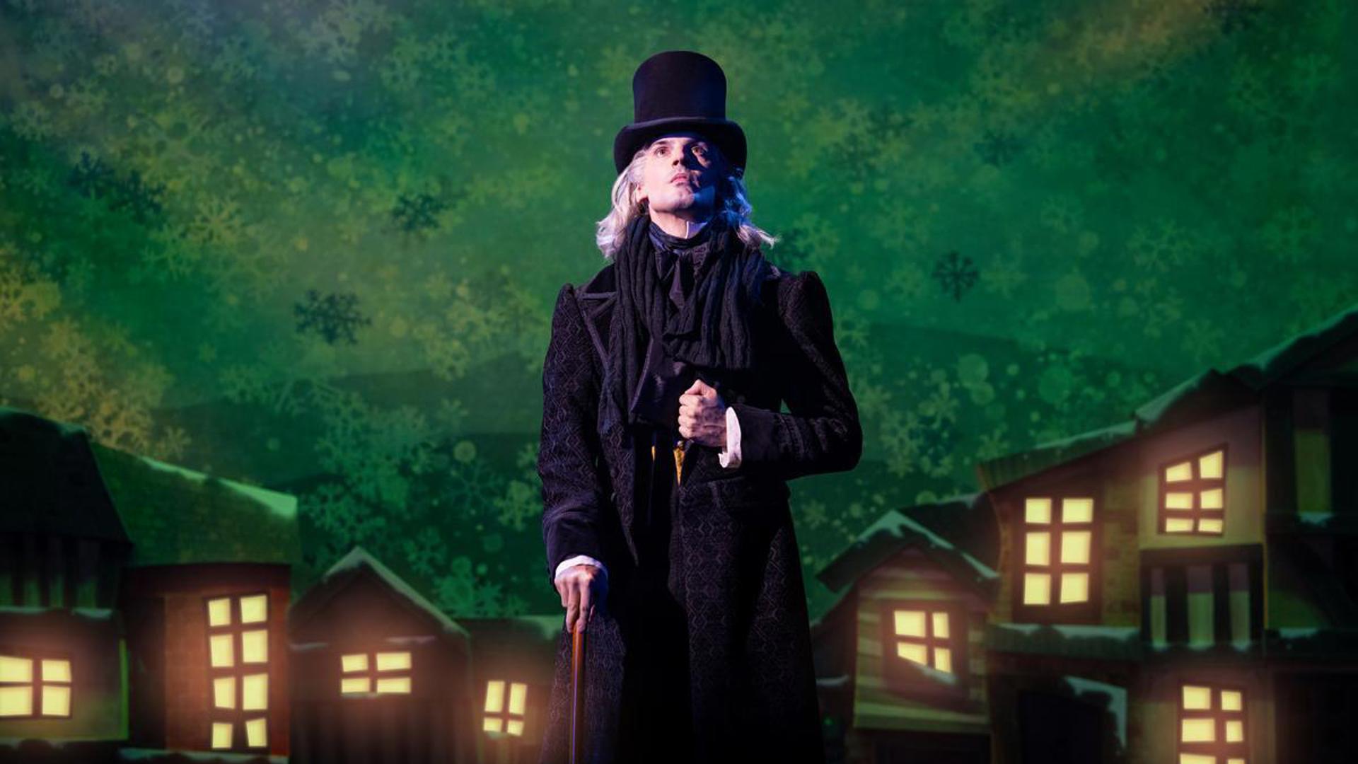 A performer stands on stage in a top hat with a cane, looking up at the sky.