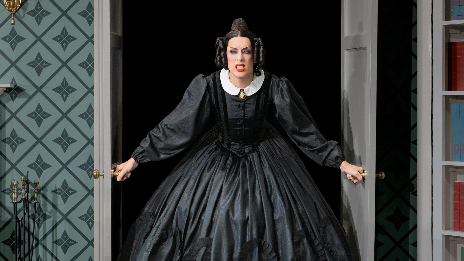 An actress in a black dress bursts through a set of double doors with a scowl on her face.