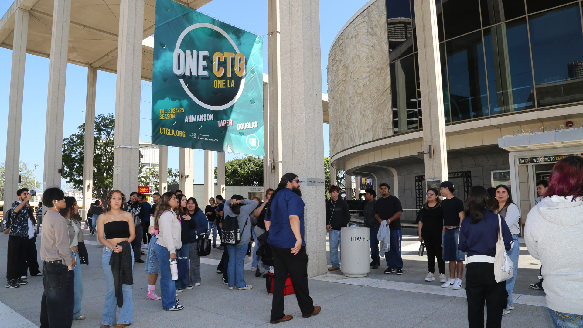 Young adults stand infront of the Mark Taper Forum during the day. 